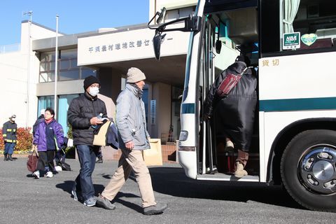 千浜農村環境改善センターに止まったバスに乗り込む避難住民ら