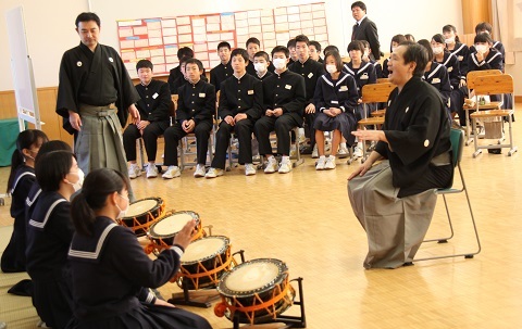 格子の指導を受けながら謡と太鼓に挑戦する生徒たち。正座で太鼓の前に座る生徒と、その様子を見守る生徒たち。