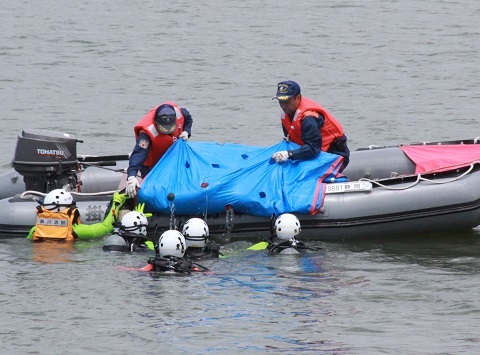 遭難者に見立てた人形を水からボートに引き上げる参加者ら