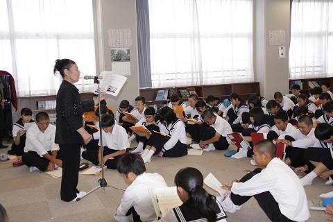 マイクで歌う鈴木敏子さんと一緒に歌の練習をする栄川中の生徒たち