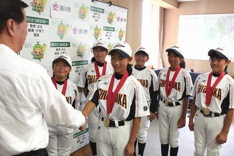 松井市長と握手をするユニフォーム姿に金メダルを下げた女子選手たちの様子。