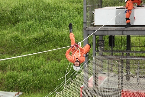 ロープブリッジ救出種目で建物の間に張られたロープを伝う救助部員の様子。