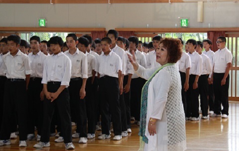 体育館内で並んで歌う生徒に向かって歌唱指導する伊達伸子さん