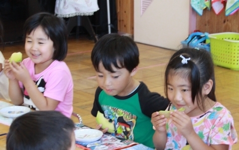 手にカットされたメロンを持って食べる園児3人