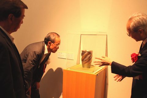 内田MOA館長から中央に置いた作品の解説を受ける松井市長と作品を近くで覗き込む男性