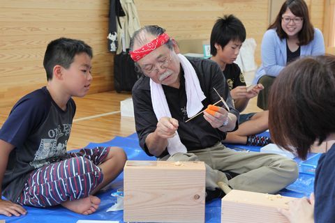 藤沼さんが竹とんぼを持ち、児童に指導をしている