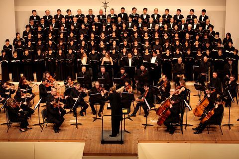 舞台の上に立つロッシーニ歌劇場管弦楽団と市民合唱団の写真