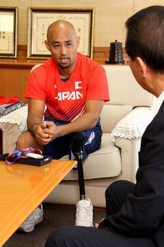 掛川市役所にて、松井市長に世界大会の結果を報告する赤いジャパンのユニフォーム姿の山本さん（男性）