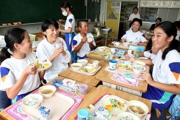 机を寄せて楽しそうに給食を味わう児童と調理員