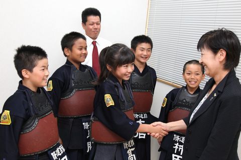 山田教育長と握手をする女子選手と剣道の防具をつけた選手たちの様子。