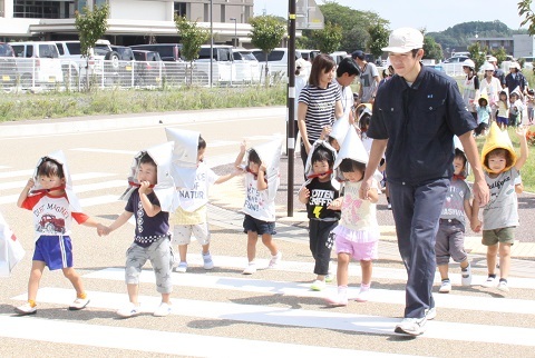 横断歩道を渡りながら園児の手を引き避難所へ誘導する特別支援学校の生徒の写真