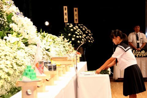 追悼式で菊の花を前に献花をする戦没者のひ孫のセーラー服の女学生