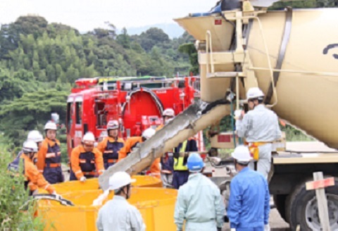 消火水をミキサー車で運び防火水槽へ給水する訓練