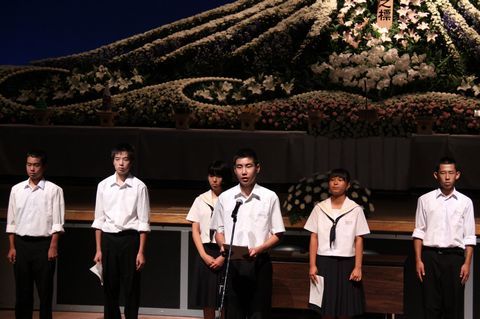 広島訪問で感じたことを発表する男子学生、後ろに男女の学生が並んでいる