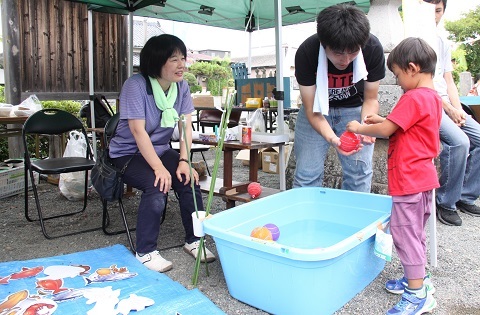 ヨーヨー釣りを楽しむ子供とそれを見守る人