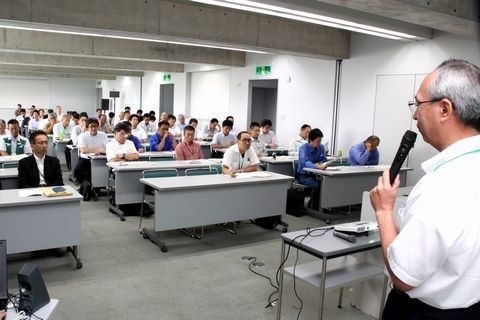 会議室にて、参加者80人の前で市の防災体制について説明する浦野危機管理課長