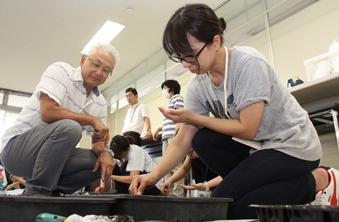 講師の伊藤さんから種まきの指導を受ける参加者。1ミリほどの種を親指と人差し指で優しくつまんで園芸用のトレイに入れている