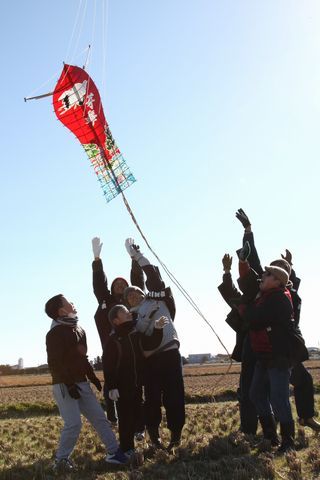 田んぼで遠州横須賀凧とんがりをあげている様子