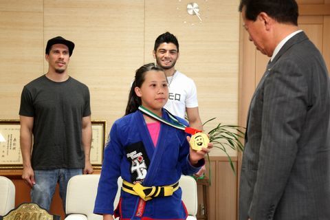 優勝した金城さんが首に掛けた金メダルを左手に持ち松井市長に披露するようす