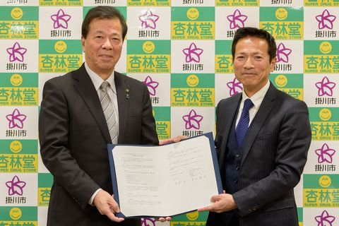 締結した協定書を2人で持つ松井市長と青田社長の写真