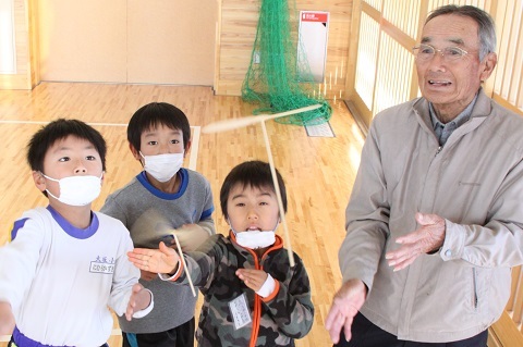 神谷さんと一緒に上手に竹とんぼを飛ばして遊ぶ3人の児童たちの写真