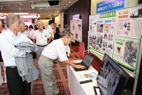 シティプロモーションの取り組み事例を披露した各団体ブースでパソコンを触る男性や掲示物をみる男性