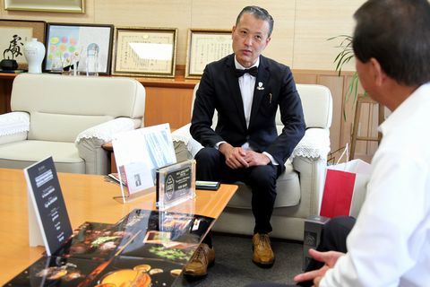 カクテル写真コンテストの作品と盾を机に並べ、松井市長（右）にコンテストの優勝の喜びを報告する篠原さん