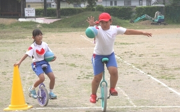 一輪車に乗ってドリブルに挑戦する児童のようす