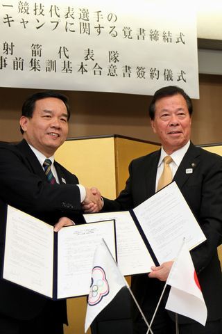 しっかりと笑顔で握手をし覚書を取り交わす松井市長と台湾アーチェリー協会副理事長の邱さんの写真