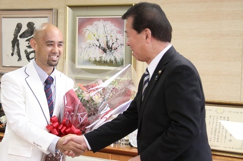 松井市長に活躍を誓い握手をしている花束を抱えた山本選手の写真