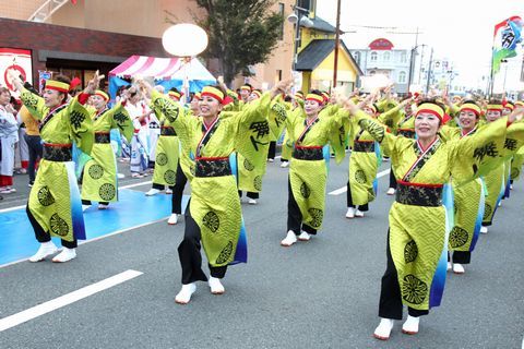 両手をあげカラフルな衣装で、いとくり通りでよさこいを披露する「遠州鳴子浪漫」のみなさん