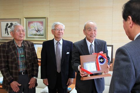 盾を持ち笑顔で松井市長に受賞を報告する3人の写真。左から石神さん、山﨑さん、榛葉さん。