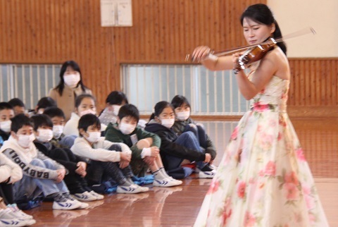 児童にヴァイオリンの演奏を披露する長尾さんの写真