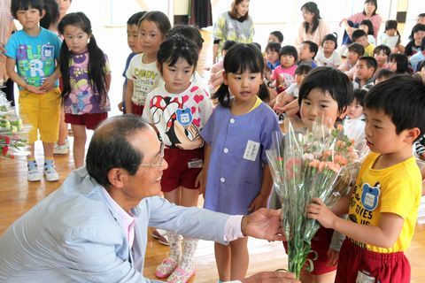 カーネーションの花束を横須賀幼稚園の園児にプレゼントする花の生産者の大場猛雄さん