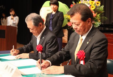 包括連携協定の協定書にサインする松井市長（右）と砂川社長