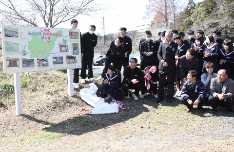 完成したばかりの案内看板を眺める生徒と東山口地区の役員の人達