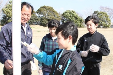 高橋さんのアドバイスでゴールポストにペンキを塗る児童ら