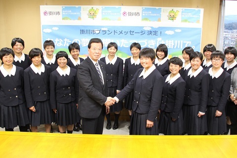 東日本大会への出場を決めたメンバーと松井市長と鈴木花音さんが握手している様子