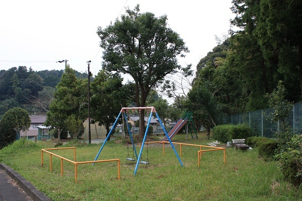 緑いっぱいの公園にブランコとすべり台が設置されている