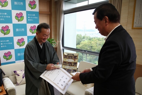 松井市長（右）から委嘱書と大使の名刺、記念品を受け取る杵屋さん