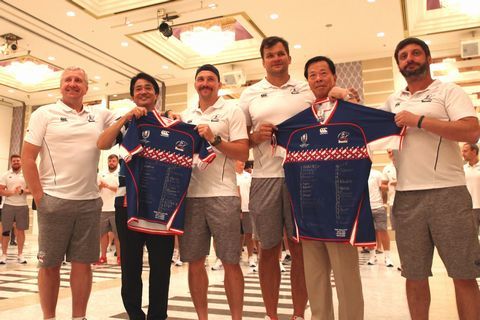 ロシア代表の全選手サイン入りユニフォームを受け取り、選手と記念撮影をするようす 松井市長(右から2番目)と磐田市の袴田部長（左から2番目）