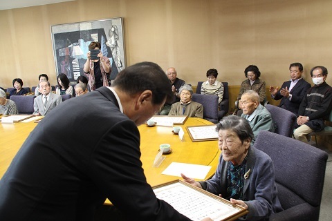 健康長寿者表彰式で、市長から表彰を受ける95歳を迎えた参加者12名の様子