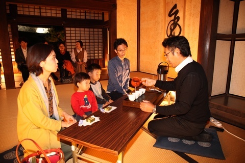 柔らかな秋の月明りに照らされた掛川城御殿内で、お茶やお菓子を頂きながら会話を楽しむ家族のようす