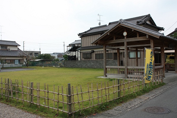 柵に囲われた芝生と屋根のある休憩所、奥には駐車場