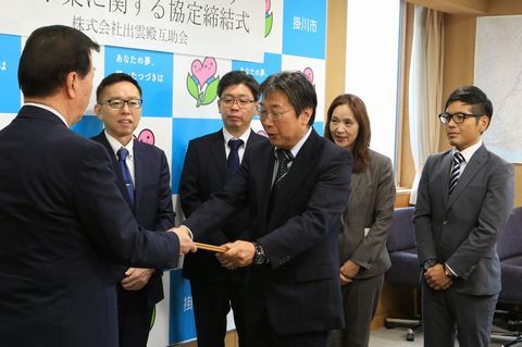 締結式で松井市長から協力事業者証を受け取っている羽田取締役の写真