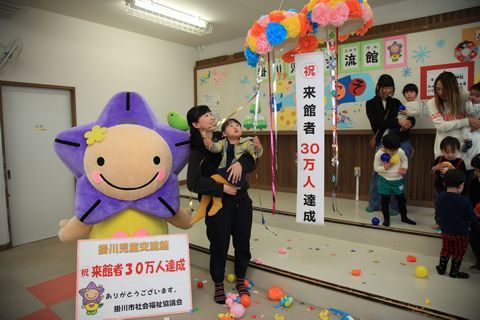 30万人目の来館者となった田中さん親子がお祝いのくす玉を割った写真