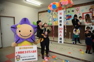 30万人目の来館者となった田中さん親子がお祝いのくす玉を割った写真