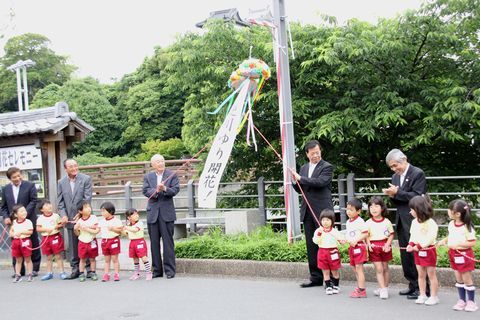 関係者や智光幼稚園園児らがくす玉を割ってユリの開花を祝う様子
