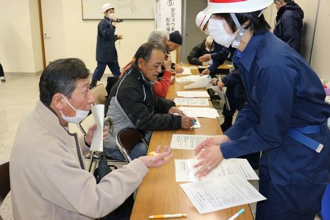 安定ヨウ素剤配布訓練に参加した住民が保健師から問診を受け、ヨウ素剤に見立てたあめを受け取る様子