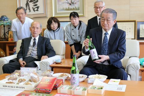市内の食品製造所など4事業所が同市伝統産業の葛を使った新商品を机に並べて、完成したことを松井市長に報告する様子